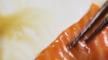 Adam Japon Chopstic 'li kırmızı balık somonu alıyor.