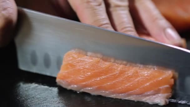 Mann schneidet roten Fischlachs auf schwarzem Brett — Stockvideo