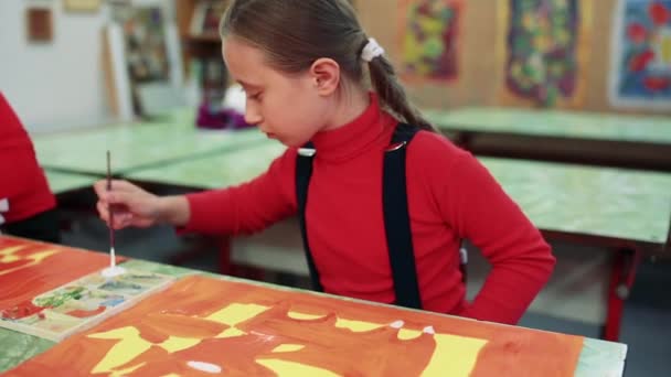 A menina desenha um quadro pinta na sala de aula — Vídeo de Stock