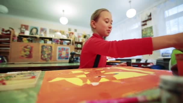 A menina desenha um quadro pinta na sala de aula — Vídeo de Stock