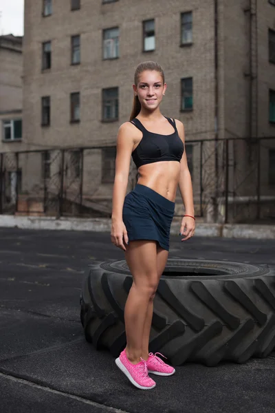 A woman standing near the wheel and smiling. athlete — Stock Photo, Image