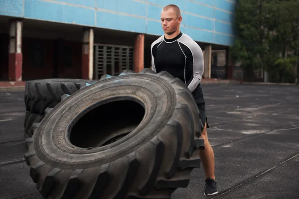 Man raises a big tire on the artificial field