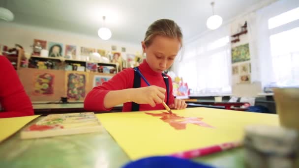 A menina desenha um quadro pinta na sala de aula — Vídeo de Stock