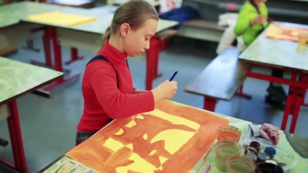 A menina desenha um quadro pinta na sala de aula — Vídeo de Stock