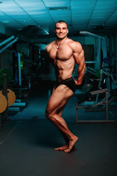 Bonito homem com grandes músculos, posando para a câmera no ginásio — Fotografia de Stock