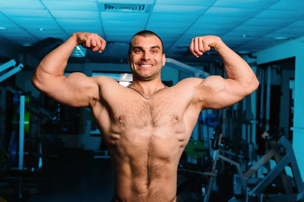 Knappe man met grote spieren, poseren bij de camera in de sportschool — Stockfoto