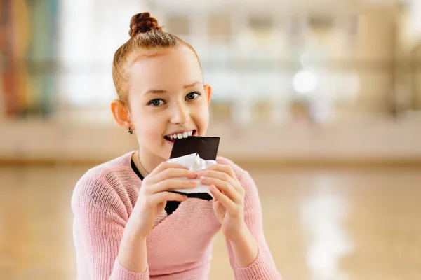 Menina bailarina comer chocolate na aula de balé — Fotografia de Stock