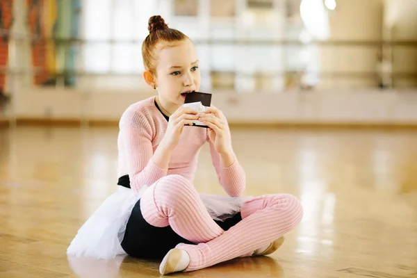 Girl ballerina eating chocolate in ballet class — Stock Photo, Image