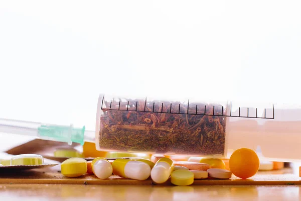 Syringe with medicinal herbs and tablets on the table. macro — Stock Photo, Image