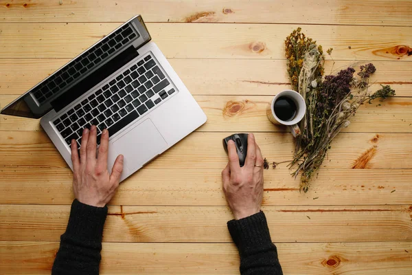 Vintage Hipster hölzerne Desktop-Ansicht, männliche Hände mit einem Laptop und einer Tasse Kaffee lizenzfreie Stockfotos