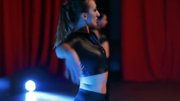 Стегна дівчат в сексуальних костюмах танцюють в освітленій сцені — стокове відео