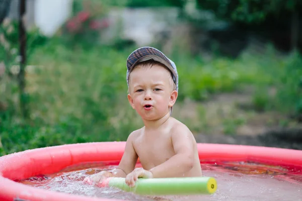 Gelukkig lachen kind spelen met water gun automatische waterpistool in buitenzwembad op zomervakantie in tropische resort. — Stockfoto