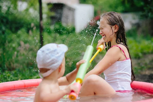 Boy shoots a water pistol in a girl — Stock Photo, Image