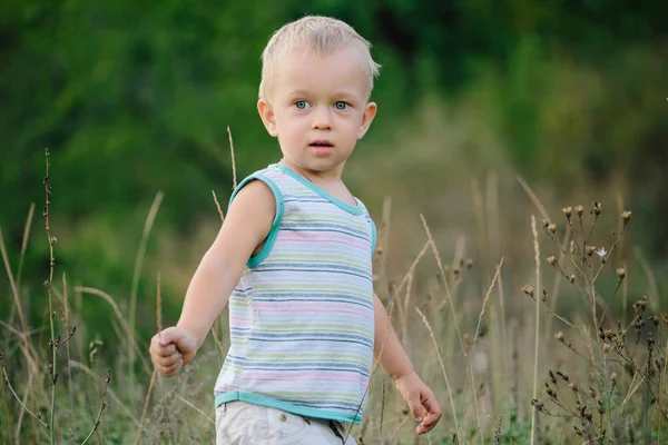 Een jongen loopt langs een open plek in het gras — Stockfoto