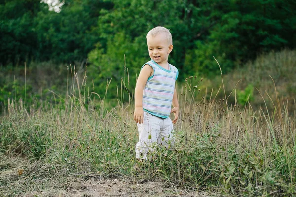 Een jongen loopt langs een open plek in het gras — Stockfoto