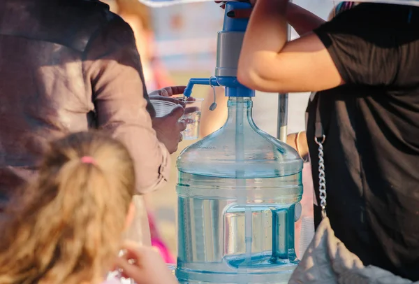 Kühler mit Wasser, Menschen geben Wasser lizenzfreie Stockfotos