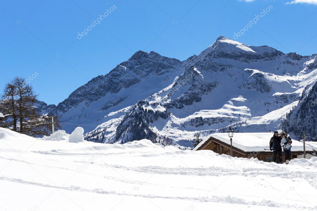 mountain cabin submerged by snow on a sunny day