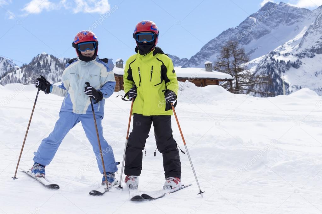 children on a ski slope with mountain background and snow