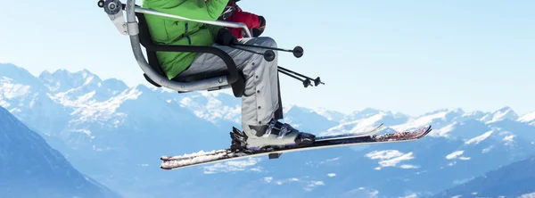 Skiërs op stoeltjeslift met besneeuwde bergen op de achtergrond — Stockfoto