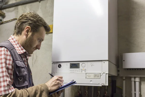 Plumber who carries out the maintenance of a condensing boiler — Stock Photo, Image