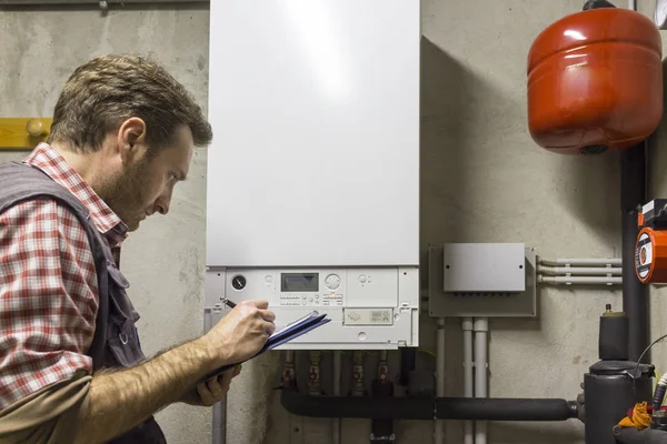 Plumber who carries out the maintenance of a condensing boiler — Stock Photo, Image