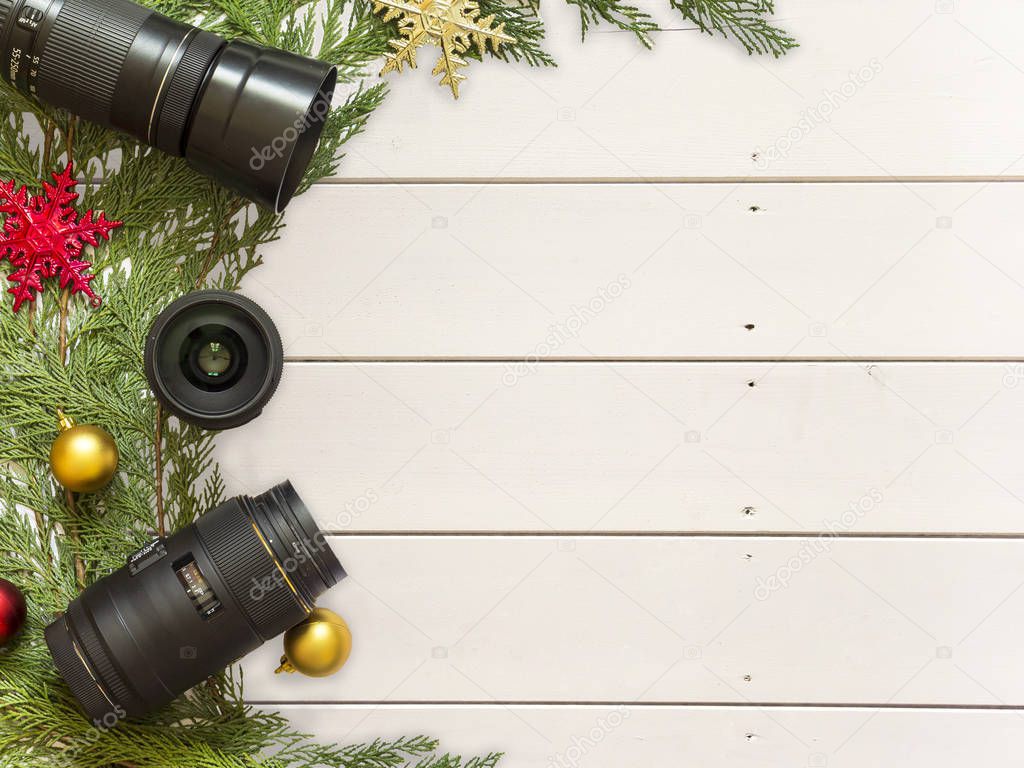 Lenses for reflex camera and Christmas decorations on a white wood background