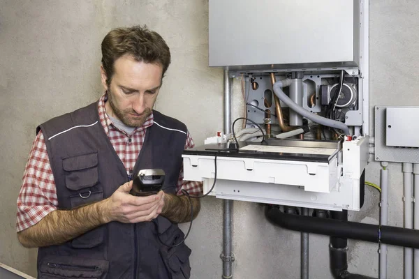 Tesisatçı, yoğunlaştırıcı kazanı tamir ediyor.