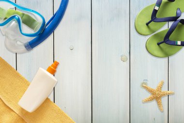 Deniz terlikleri, tüplü maske ve denizyıldızı ışık mavi ahşap arka plan üzerinde