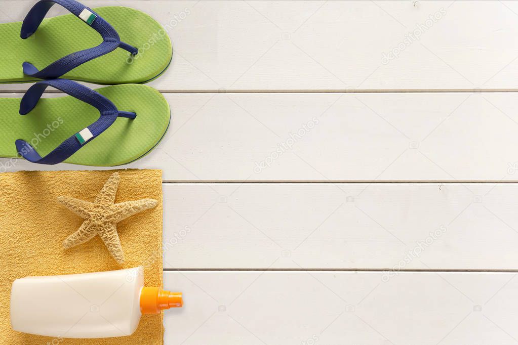 Sea slippers, sunscreen and towel on wooden background