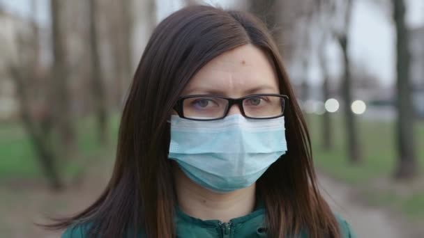 Una giovane ragazza in occhiali e maschera medica si trova sulla strada . — Video Stock