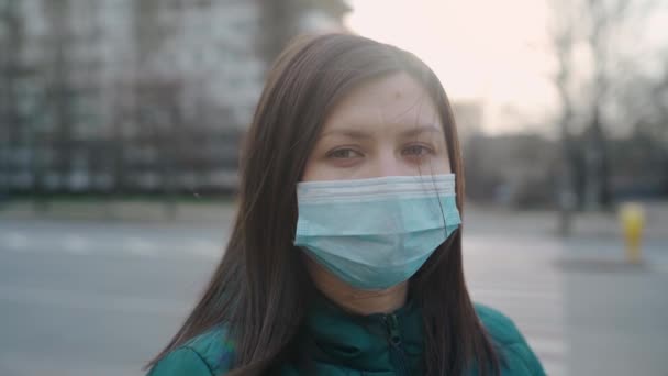Uma jovem de óculos e máscara médica fica na rua . — Vídeo de Stock