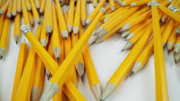 Žluté tužky leží chaoticky na bílém pozadí, makro záběr na laowa 24 mm — Stock video