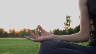 Gün batımında yeşil çimlerde meditasyon yaparken namaste Mudra pozu veren bir kıza ellerini uzat..