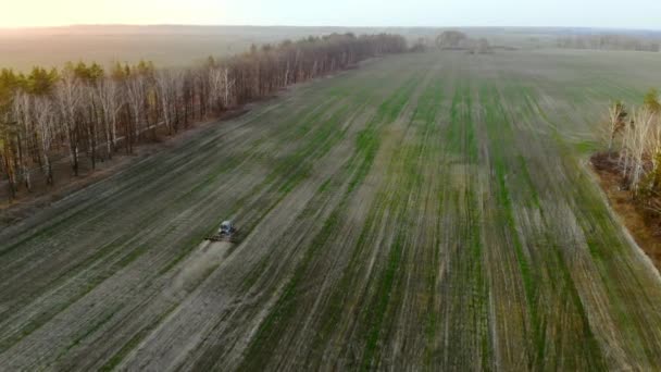 Vista aérea, trator agrícola arado um campo ao pôr do sol . — Vídeo de Stock