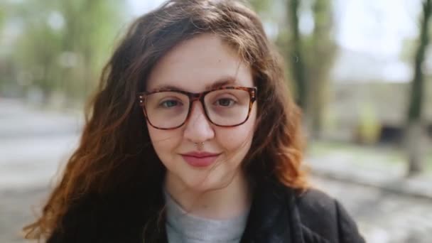 Chica pelirroja en gafas mirando a la cámara y sonriendo . — Vídeo de stock