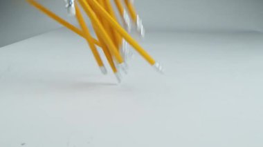 Sarı kalemler beyaz bir masaya ağır çekimde düşüyor..