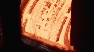 Taşıyıcı üzerinde kırmızı-sıcak metal levha döner. Yavaş hareketler.