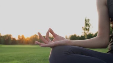 Gün batımında yeşil çimlerde meditasyon yaparken namaste Mudra pozu veren bir kıza ellerini uzat..