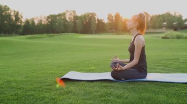 Yeşil çimlerin üzerinde yoga yapan genç bir kız.
