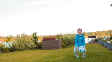 Evinin bahçesinde topuyla oynayan çocuk