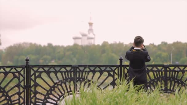 Мальчик фотографирует пейзаж с моста — стоковое видео