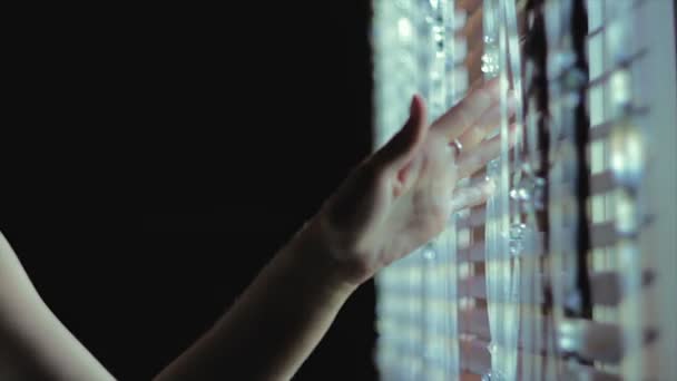 Девушка держит руку над стеклянным занавесом — стоковое видео