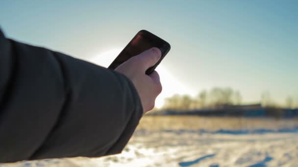 Человек использует телефон на холоде — стоковое видео