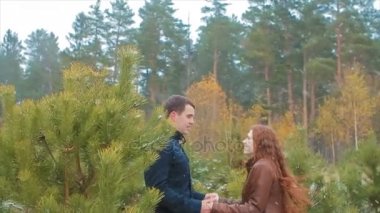 Genç çift el ele tutuşarak kar ormanında sonbahar atlar