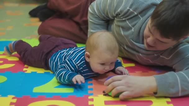 Μωρό και πατέρας του ξαπλωμένο στο πάτωμα αναπαράγω Πασχαλίτσα παιχνίδι — Αρχείο Βίντεο