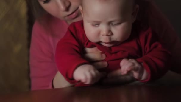 Jovem mãe brincando com seu bebê em casa sentada na mesa — Vídeo de Stock