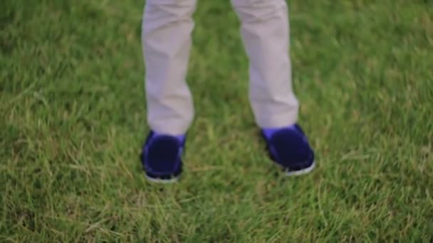 Niño gotas bola en hierba en frente de su pies — Vídeo de stock