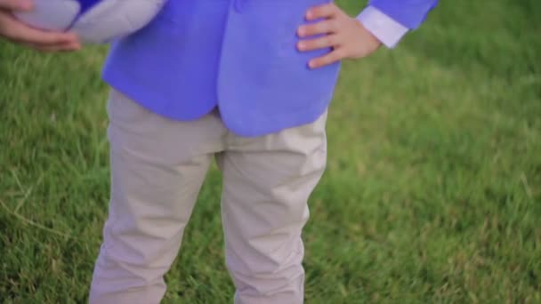 Niño en chaqueta sostiene pelota de fútbol bajo su brazo — Vídeo de stock