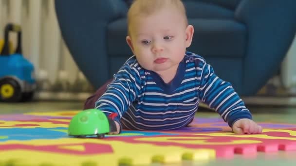 Baby liegt auf Matte neben Spielzeug — Stockvideo