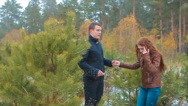 Menina e seu namorado ficar em bosques de outono entre pequenos pinheiros câmera lenta — Vídeo de Stock